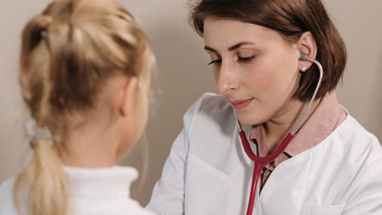 A doctor checking a young child with a stethoscope