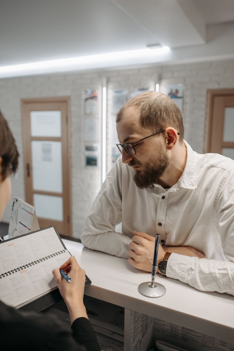 A patient talking with the receptionist at a clinic front desk